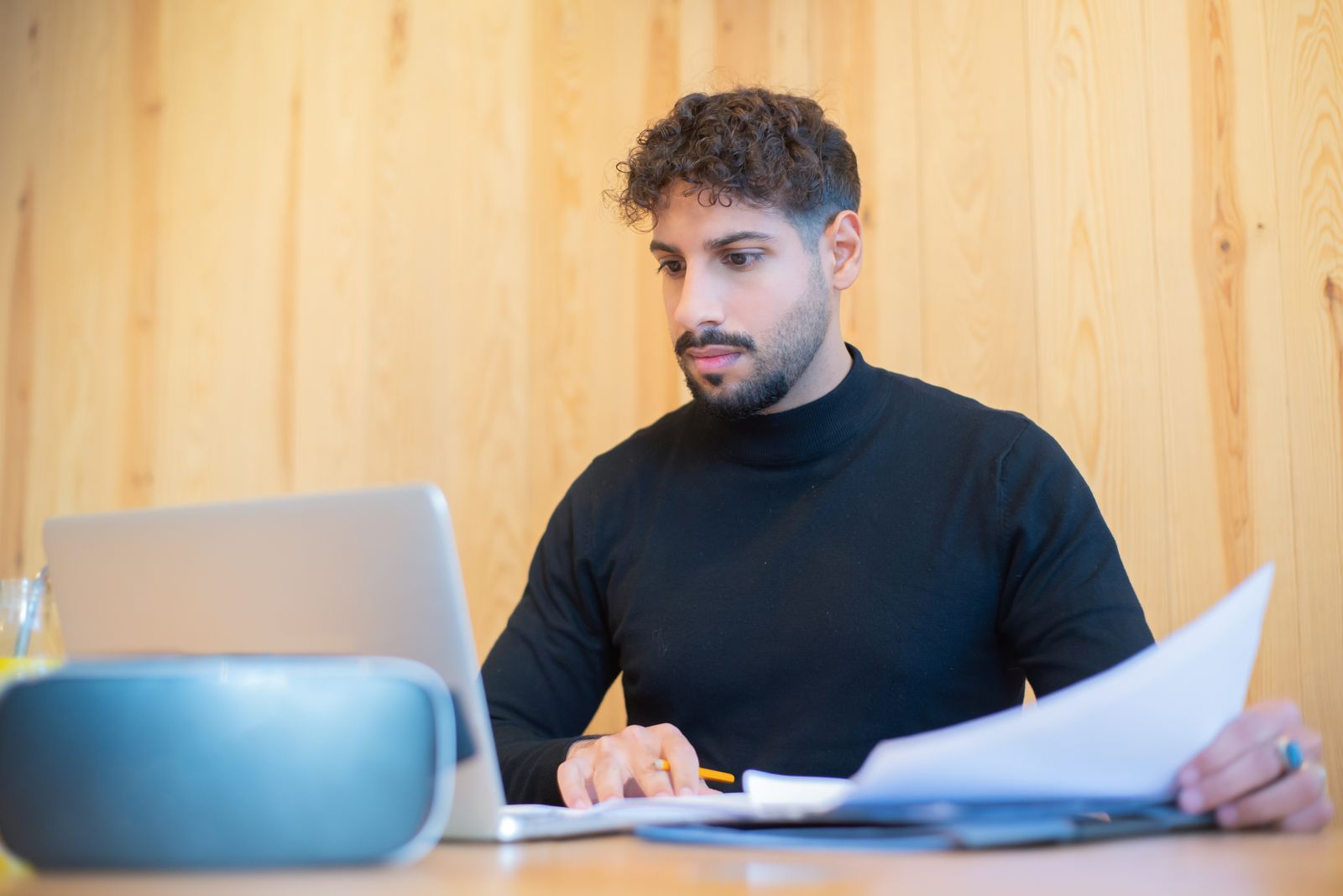 Professional reviewing documents beside a laptop