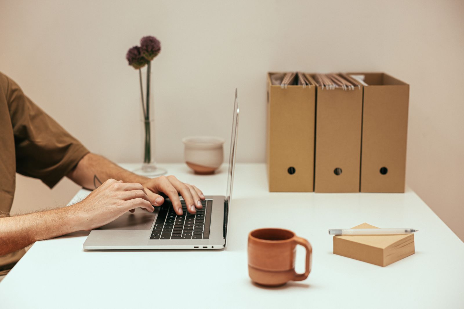 Hands using a laptop beside organized office files